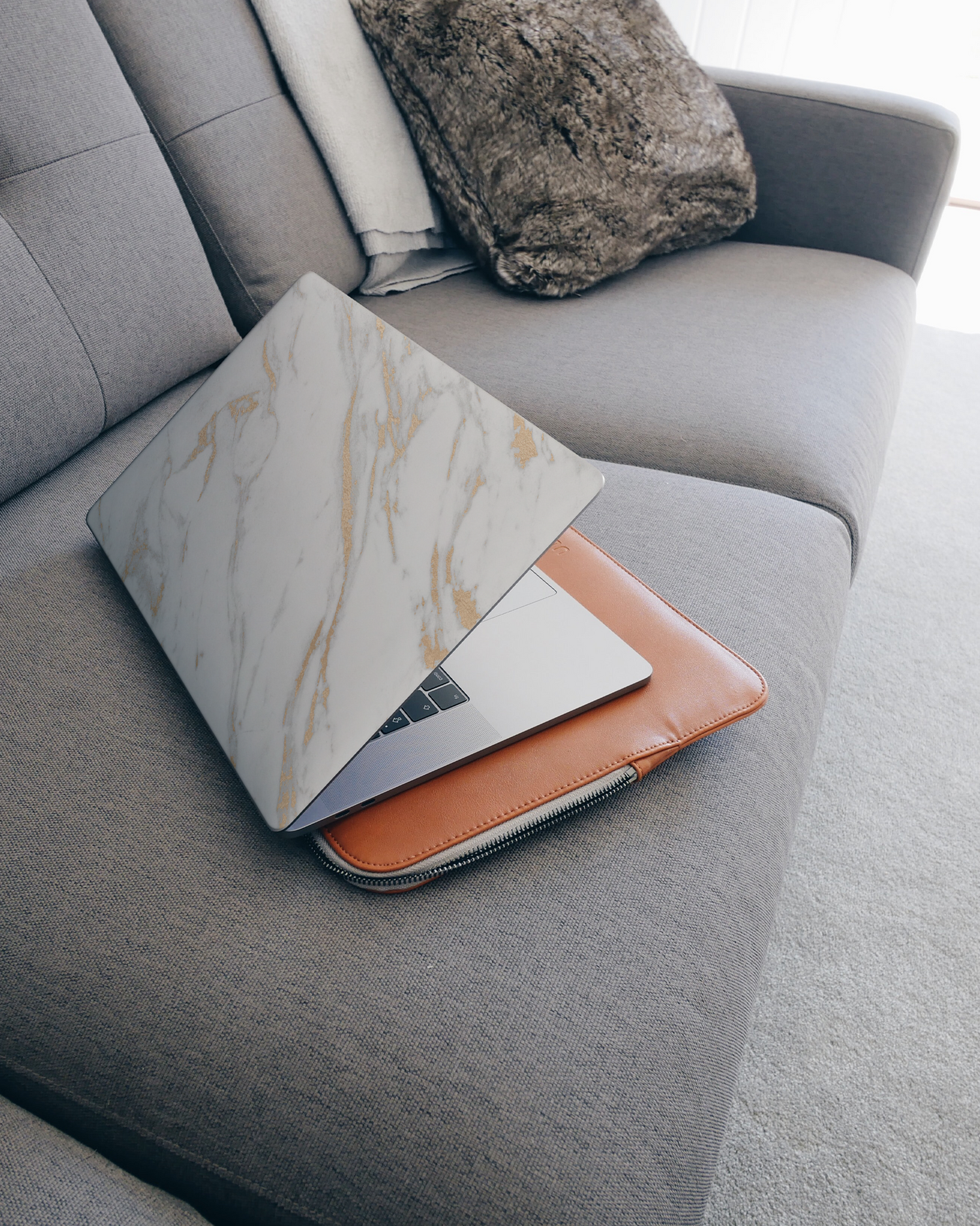 Gold Marble Elegance Laptop Aufkleber für 15 Zoll Apple MacBooks auf dem Sofa